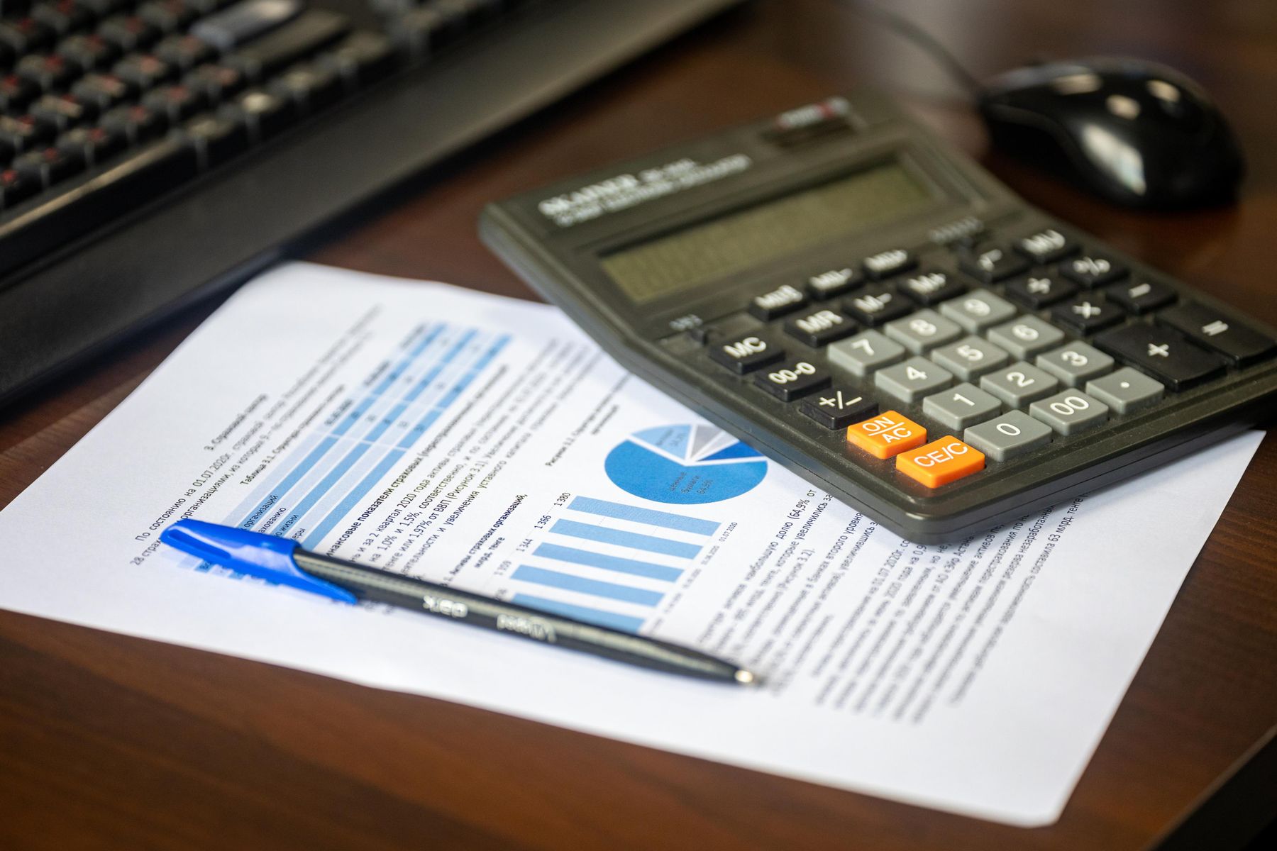 Printed financial analysis with charts beside a calculator and pen